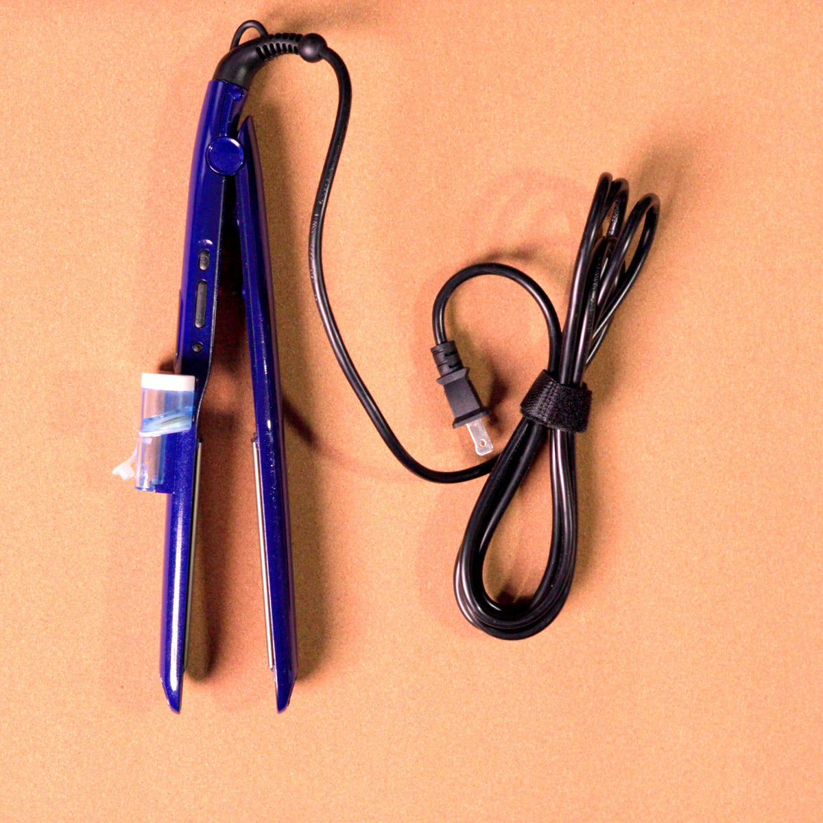 Plancha Lisfashion Biónica azul con depósito para ampolleta y cable, vista superior sobre la mesa